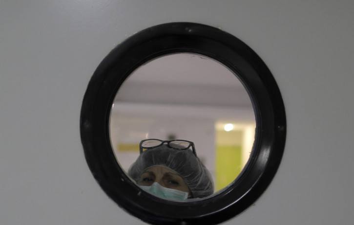 A health worker wearing a face mask to protect from coronavirus, looks out of from a window at a nursing home in Madrid, Spain, Tuesday, March 31, 2020.