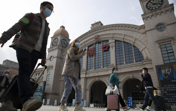 Travelers with their luggage walk past the Hankou railway station on the eve of its resuming outbound traffic in Wuhan in central China's Hubei province on Tuesday, April 7, 2020.