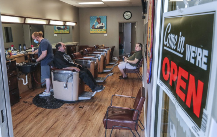 Barber and owner of Chris Edwards, left, wears a mask and cuts the hair of customer at Peachtree Battle Barber Shop in Atlanta on Friday, April 24, 2020.