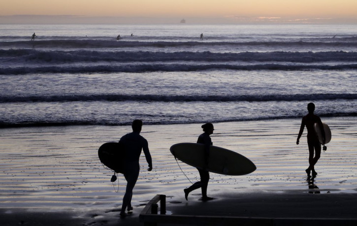 Surfers prepare to enter the water at Sumner Beach as level four COVID-19 restrictions are eased in Christchurch, New Zealand, Tuesday, April 28, 2020.