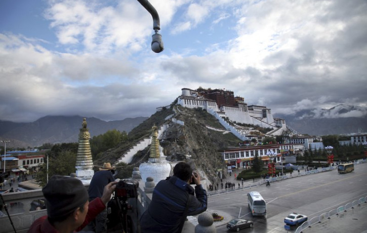 In this Sept. 19, 2015, file photo, tourists take photos of the Potala Palace beneath a security camera in Lhasa, capital of the Tibet Autonomous Region of China.