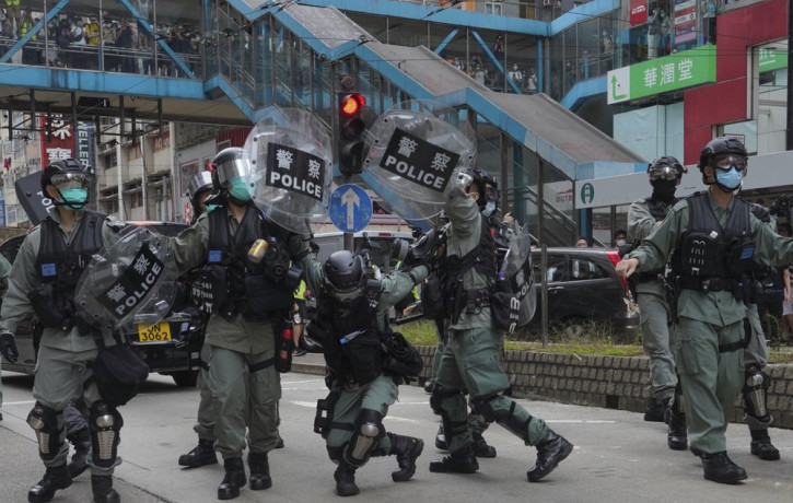 Riot police cover themselves with shields as hundreds of protesters march along a downtown street during a pro-democracy protest against Beijing's national security legislation in Hong Kong, 