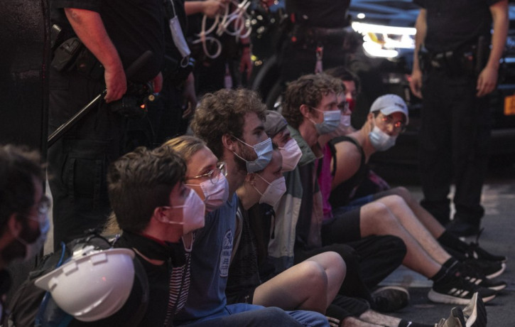 Protesters who were arrested by police for breaking a curfew during a solidarity rally calling for justice over the death of George Floyd, sit on a sidewalk as they wait to be taken away in a