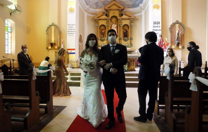 Bride Jazmin Sanabria and her groom Joel Adorno, wearing protective face masks amid the new coronavirus pandemic, walk down the aisle in the first wedding ceremony since 101 days of quarantin