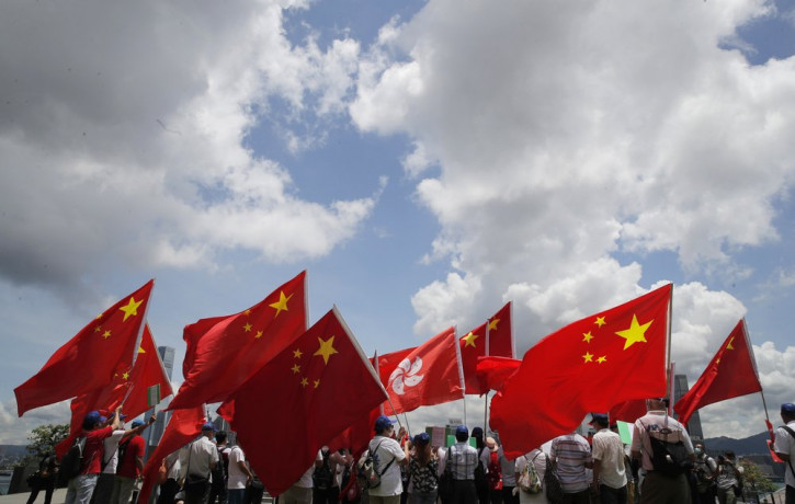 Pro-China supporters hold Chinese and Hong Kong national flags during a rally to celebrate the approval of a national security law for Hong Kong, in Hong Kong, Tuesday, June 30, 2020.