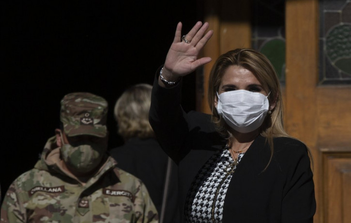 Bolivia's interim President Jeanine Anez, wearing a face mask to help curb the spread of the new coronavirus, waves during a procession Corpus Christi, in La Paz, Bolivia, Thursday, June 11, 