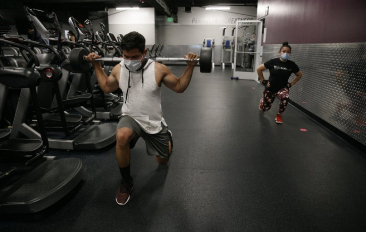 In this June 26, 2020 file photo, people wear masks while exercising at a gym in Los Angeles. On Thursday, July 9, 2020, the WHO is acknowledging the possibility that COVID-19 might be spread