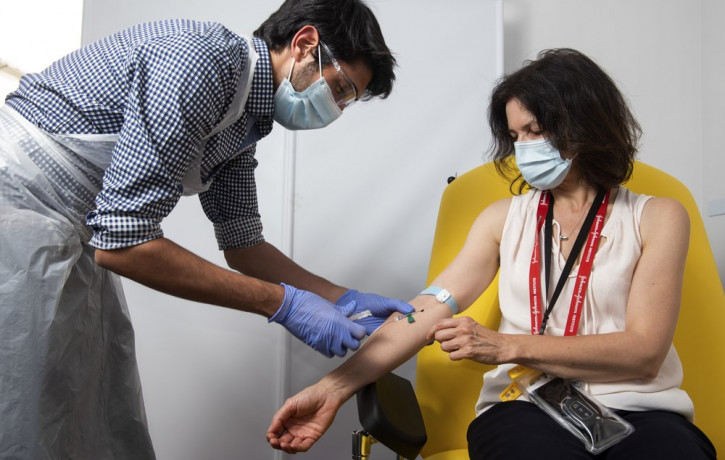 In this handout photo released by the University of Oxford a doctor takes blood samples for use in a coronavirus vaccine trial in Oxford, England, Thursday June 25, 2020.