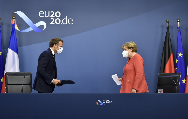 German Chancellor Angela Merkel, right, and French President Emmanuel Macron prepare to address a media conference at the end of an EU summit in Brussels, Tuesday, July 21, 2020.