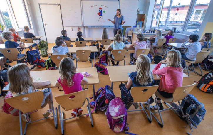 Teacher Francie Keller welcomes the pupils of class 3c in her classroom in the Lankow primary school to the first school day after the summer holidays in Schwerin, Germany, Monday, Aug. 3, 20