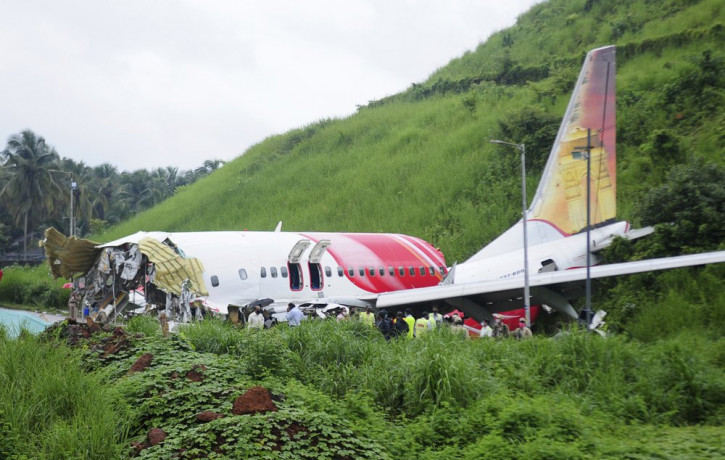 Officials stand on the debris of the Air India Express flight that skidded off a runway while landing in Kozhikode, Kerala state, India, Saturday, Aug. 8, 2020.