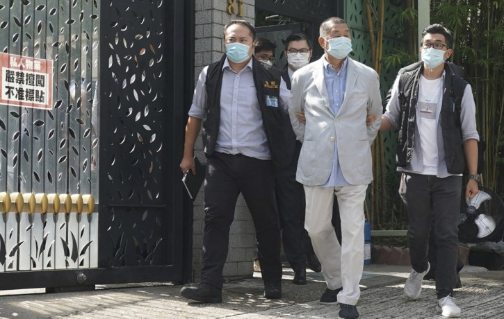 Hong Kong media tycoon Jimmy Lai, center, who founded local newspaper Apple Daily, is arrested by police officers at his home in Hong Kong, Monday, Aug. 10, 2020.