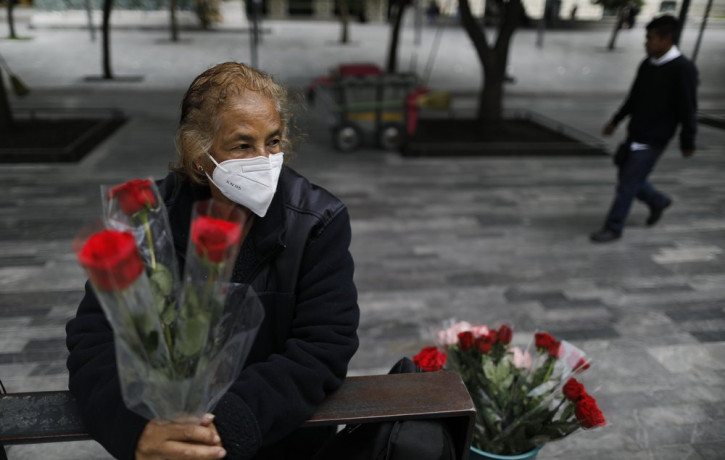 Wearing a mask to curb the spread of the new coronavirus, Martha Gonzalez Reyes, 76, sells roses outside Metro Hidalgo in central Mexico City, Monday, Aug. 10, 2020.
