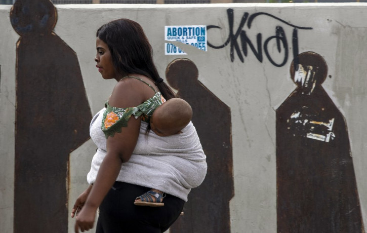 A  woman carrying her baby walks along a downtown street in Johannesburg, South Africa, Monday, March 16, 2020.