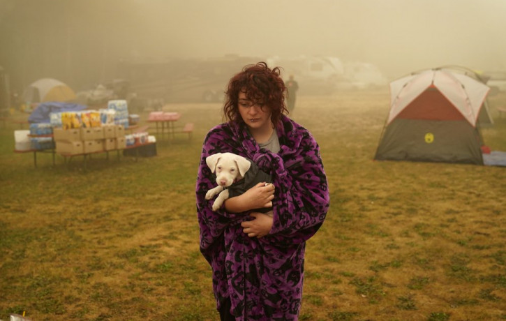 Shayanne Summers holds her dog Toph while wrapped in a blanket after several days of staying in a tent at an evacuation center at the Milwaukie-Portland Elks Lodge, Sunday, Sept. 13, 2020, in