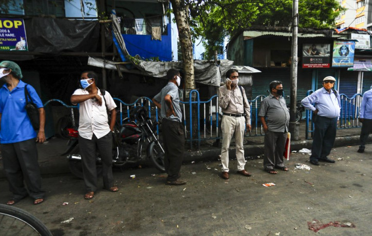 People wearing face masks to prevent the spread of the coronavirus stand maintaining social distance at a bust stop in Kolkata, India, Tuesday, Sept. 15, 2020.