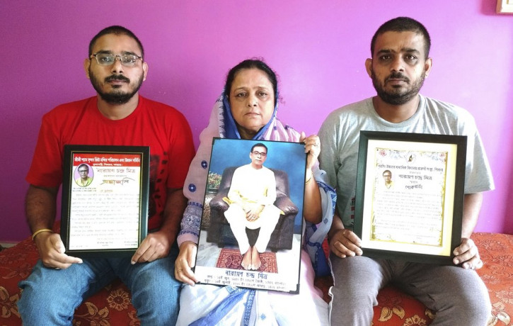 Anindita Mitra, 61, flanked by her sons Satyajit Mitra, right and Abhijit Mitra, pose with portraits of her husband late Narayan Mitra, at her house in Silchar, India, Sunday, Sept. 13, 2020.