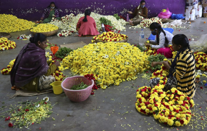 Flower vendors, some wearing face masks as a precaution against coronavirus, prepare garlands at a wholesale market in Bengaluru, India, Thursday, Sept. 24, 2020.