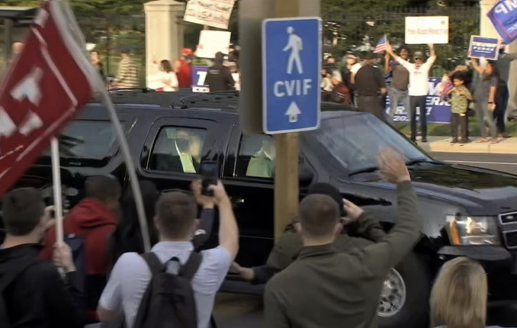 In this image from video, President Donald Trump waves as he drives past supporters gathered outside Walter Reed National Military Medical Center in Bethesda, Md., Sunday, Oct. 4, 2020.