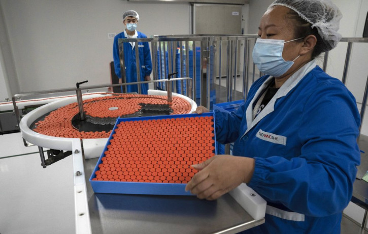 In this Sept. 24, 2020, file photo, a worker feeds vials for production of SARS CoV-2 Vaccine for COVID-19 at the SinoVac vaccine factory in Beijing.