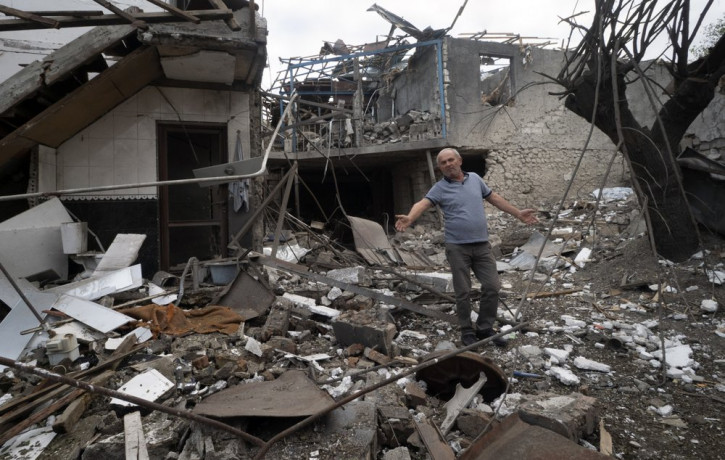 A man gestures in the yard of a house destroyed by shelling by Azerbaijan's artillery during a military conflict in Stepanakert, the separatist region of Nagorno-Karabakh, Friday, Oct. 9, 202