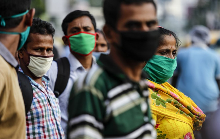 Commuters wearing face masks as a precautionary measure against the coronavirus wait for a bus in Kolkata, India, Saturday.