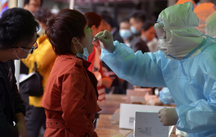 A medical staff takes a swab from a woman as residents line up for the COVID-19 test near the residential area in Qingdao in east China's Shandong province on Monday, Oct. 12, 2020.