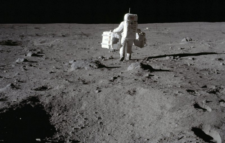 In this July 20, 1969 photo made available by NASA, lunar module pilot Buzz Aldrin carries a seismic experiments package in his left hand and the Laser Ranging Retroreflector to the deploymen