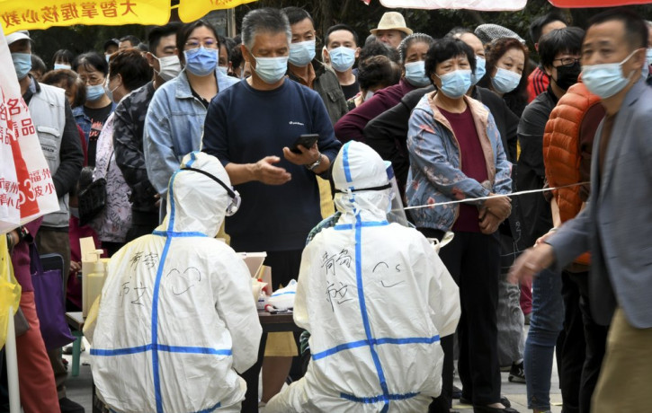 In this photo released by Xinhua News Agency, residents wearing face masks to help curb the spread of the coronavirus line up for the COVID-19 test near the residential area in Qingdao in eas