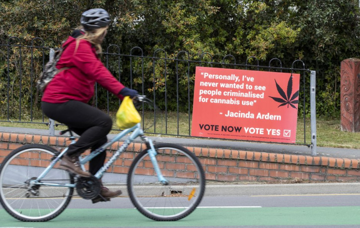 A cyclist rides past a sign in support of making marijuana legal in Christchurch, New Zealand, Thursday, Oct. 15, 2020.