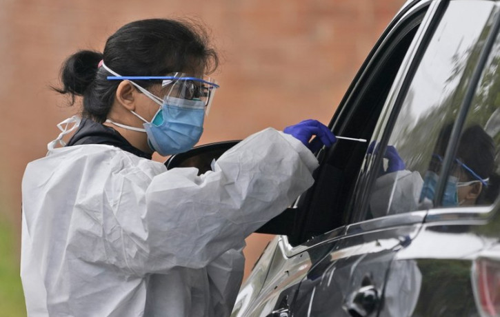 Medical personnel prepare to administer a COVID-19 swab at a drive-through testing site in Lawrence, N.Y., Wednesday, Oct. 21, 2020.
