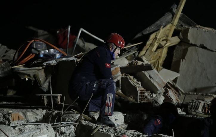 A member of rescue services, kneels to listen during the ongoing search for survivors in the debris of a collapsed building in Izmir, Turkey, Saturday, Oct. 31, 2020.