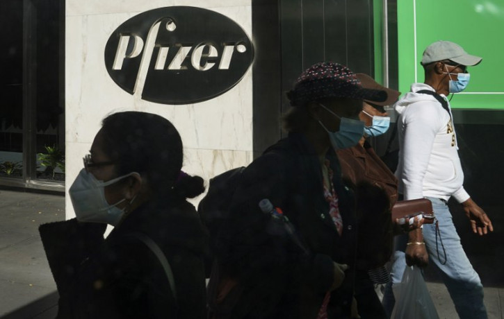 Pedestrians walk past Pfizer world headquarters in New York on Monday Nov. 9, 2020. Pfizer says an early peek at its vaccine data suggests the shots may be 90% effective at preventing COVID-1