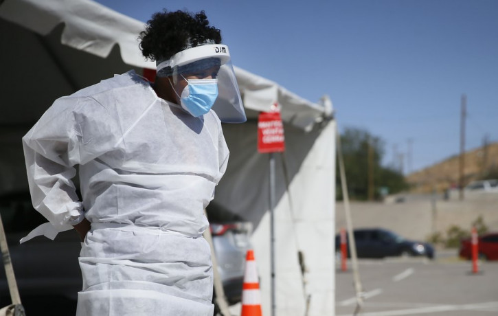 In this Oct. 26,2020, file photo, a medical worker stands at a COVID-19 state drive-thru testing site at UTEP, in El Paso, Texas.