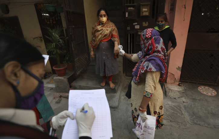 A health worker reads the temperature of a woman during a door to door survey to assess the COVID-19 situation in New Delhi, India, Monday, Nov. 23, 2020.
