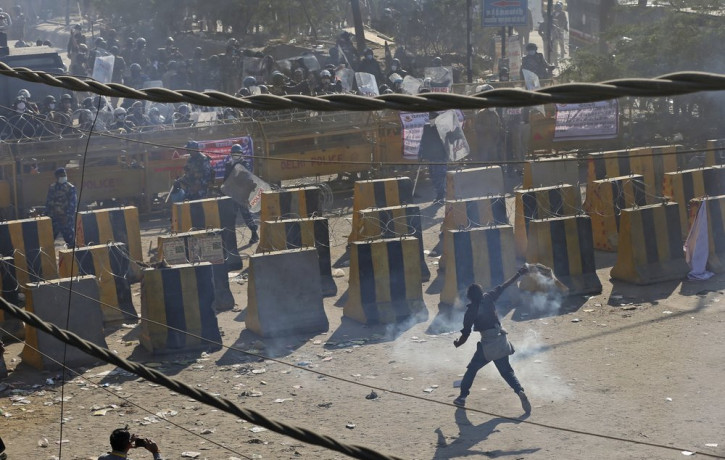 A farmer throws back a tear gas shells towards policemen, at the border between Delhi and Haryana state, Friday, Nov. 27, 2020.