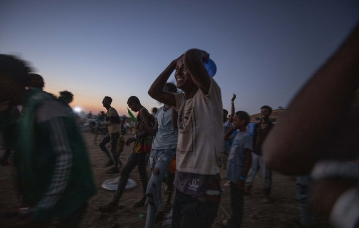 Tigray men who fled the conflict in Ethiopia's Tigray region, run to recieve cooked rice from charity organization Muslim Aid, at Umm Rakouba refugee camp in Qadarif, eastern Sudan, Friday, N