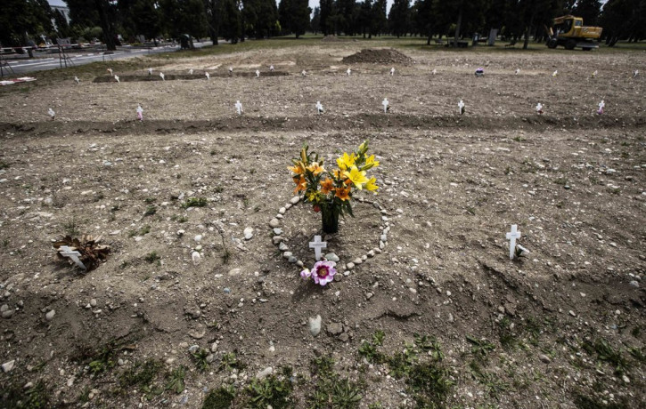 In this May 8, 2020 file photo, flowers and stones placed in the shape of a heart are laid on a burial site as white crosses are scattered at the Campo 81, an area created to host COVID-19 vi