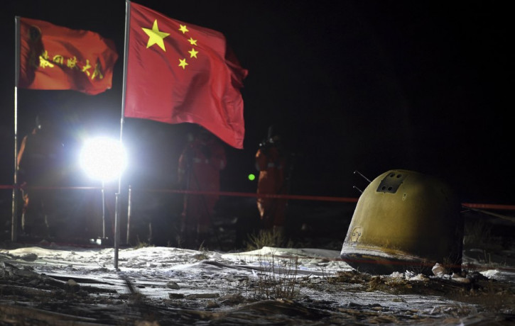 In this photo released by Xinhua News Agency, recovery crew members film the capsule of the Chang'e 5 probe after its successful landed in Siziwang district, north China's Inner Mongolia Auto