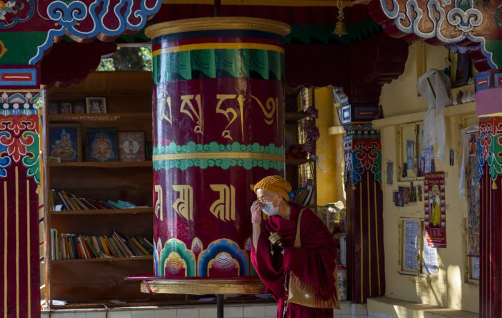 An exile Tibetan Buddhist monk wearing a mask as precaution against the coronavirus rotates a prayer wheel in Dharmsala, India, Friday, Dec. 18, 2020.