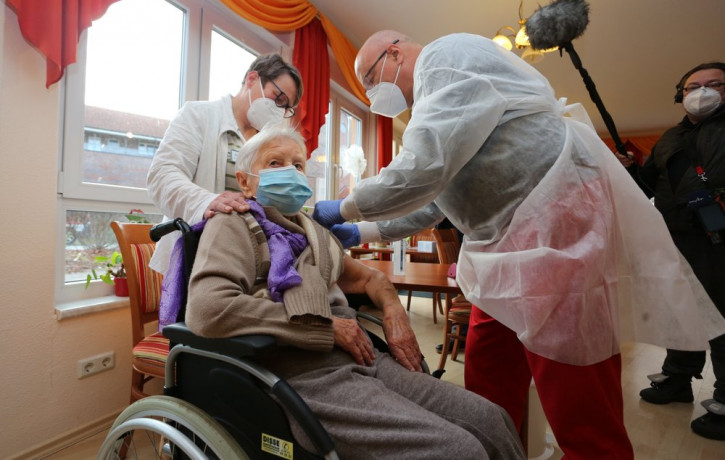 Doctor Bernhard Ellendt, right, injects the COVID-19 vaccine to nursing home resident Edith Kwoizalla, 101 years old, in Halberstadt, Germany, Saturday, Dec. 26, 2020.