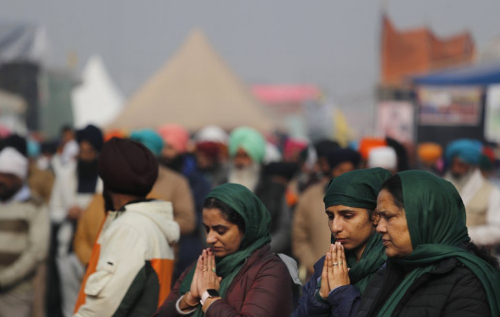 Women farmers pray during a gathering in protest against new farm laws at the Delhi-Haryana state border, on the outskirts of New Delhi, India, Sunday, Dec. 27, 2020.
