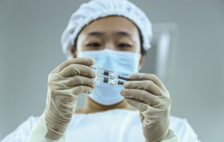 In this Dec. 25, 2020 file photo, a staff member inspects syringes of COVID-19 inactivated vaccine products at a packaging plant of the Beijing Biological Products Institute Co., Ltd, a unit 