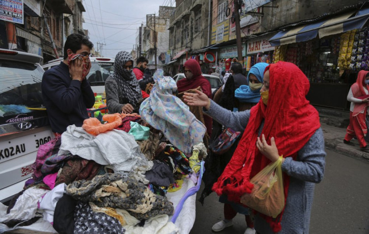 Indians, some of them, wearing face masks as a precautionary measure against the coronavirus shop at a Sunday market in Jammu, India, Sunday, Jan.3, 2021.
