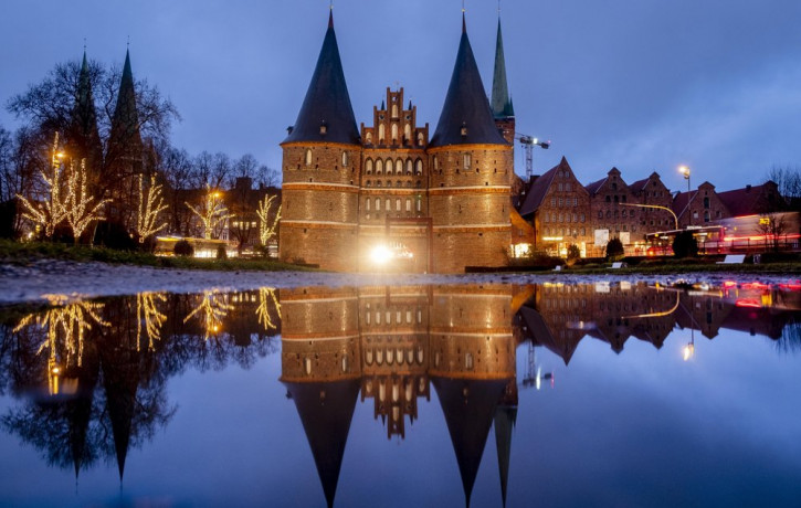 The medieval Holstentor is reflected in water in Luebeck, Germany, Monday, Jan. 4, 2021. The German government will decide about further restrictions to avoid the outspread of coronavirus on 