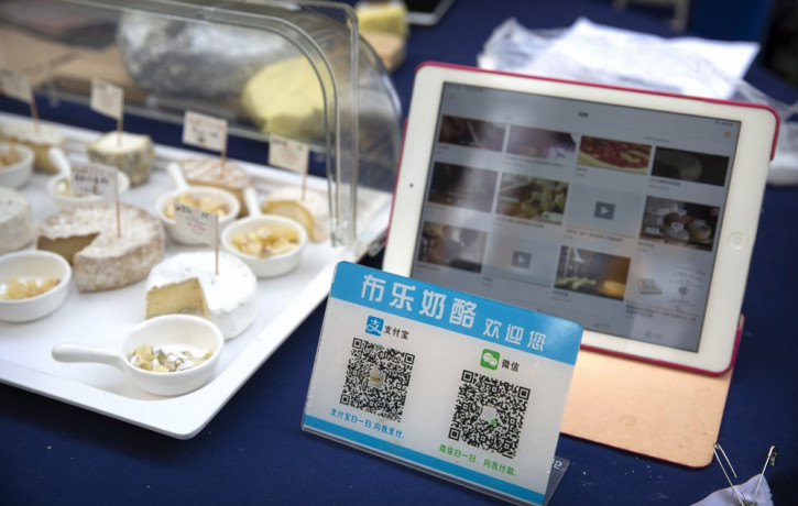 A card displaying QR codes to pay electronically with WeChat Pay and Alipay sits on a vendor's table at a farmer's market in Beijing, Tuesday, Oct. 27, 2020.