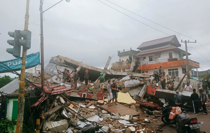 Residents inspect earthquake-damaged buildings in Mamuju, West Sulawesi, Indonesia, Friday, Jan. 15, 2021.