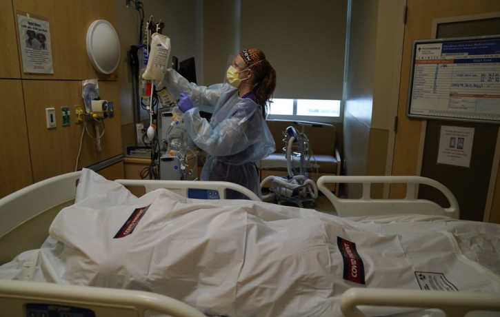Registered nurse Nikki Hollinger cleans up a room as a body of a COVID-19 victim lies in a body bag labeled with stickers at Providence Holy Cross Medical Center in the Mission Hills section 