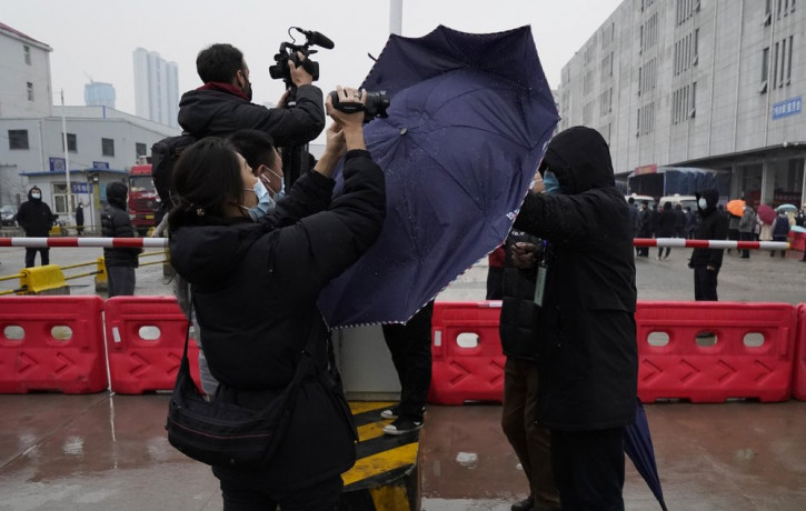 A plainclothes security person uses his umbrella to block journalists from filming after the WHO team arrives at the Baishazhou wholesale market on the third day of field visit in Wuhan in ce
