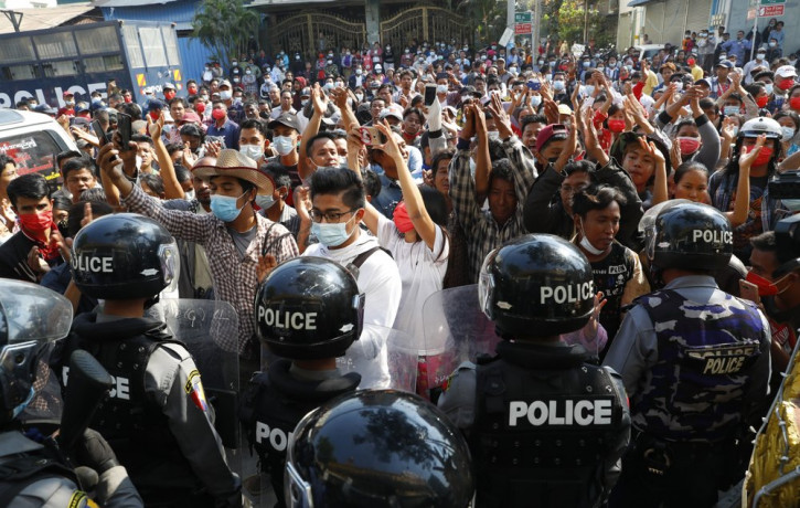 Residents and protesters face riot police as they question them about recent arrests made in Mandalay, Myanmar, Saturday, Feb. 13, 2021.